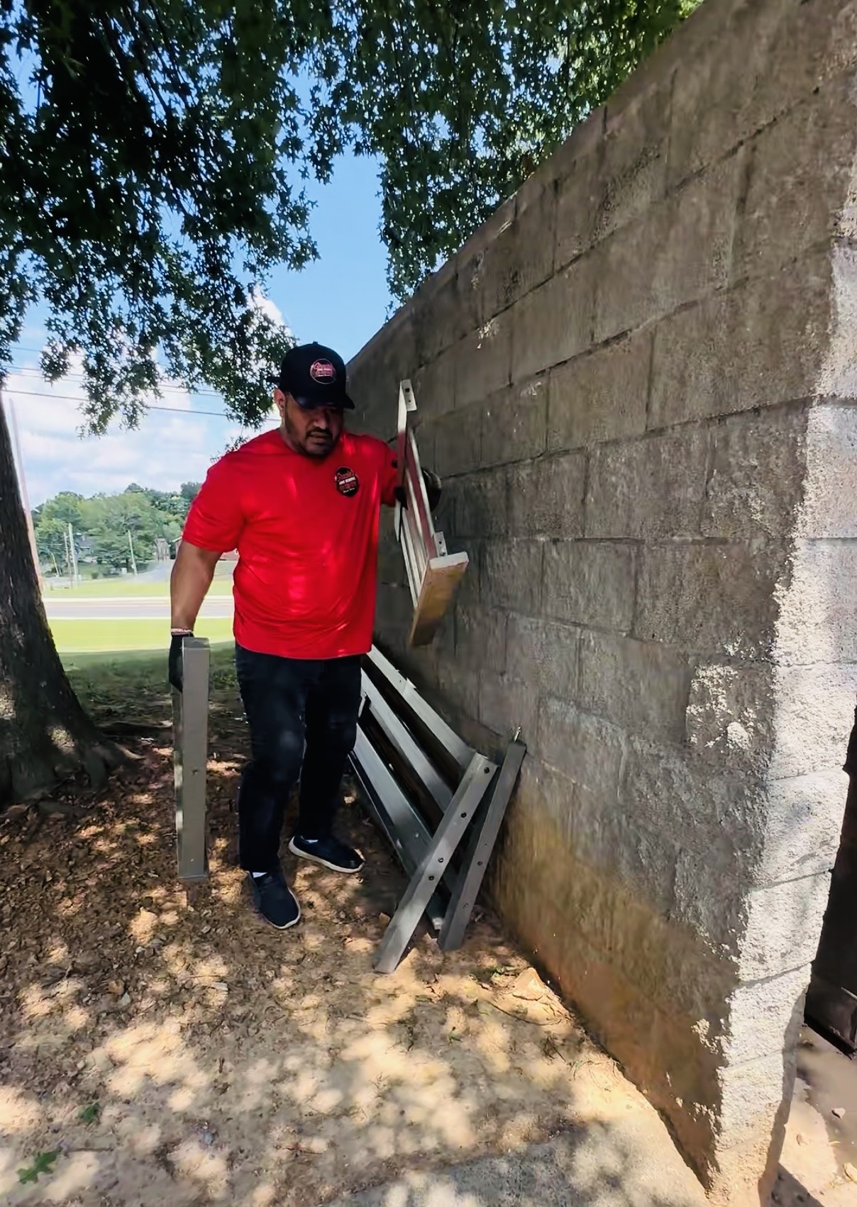 Gracie’s team member clearing outdoor debris beside a wall